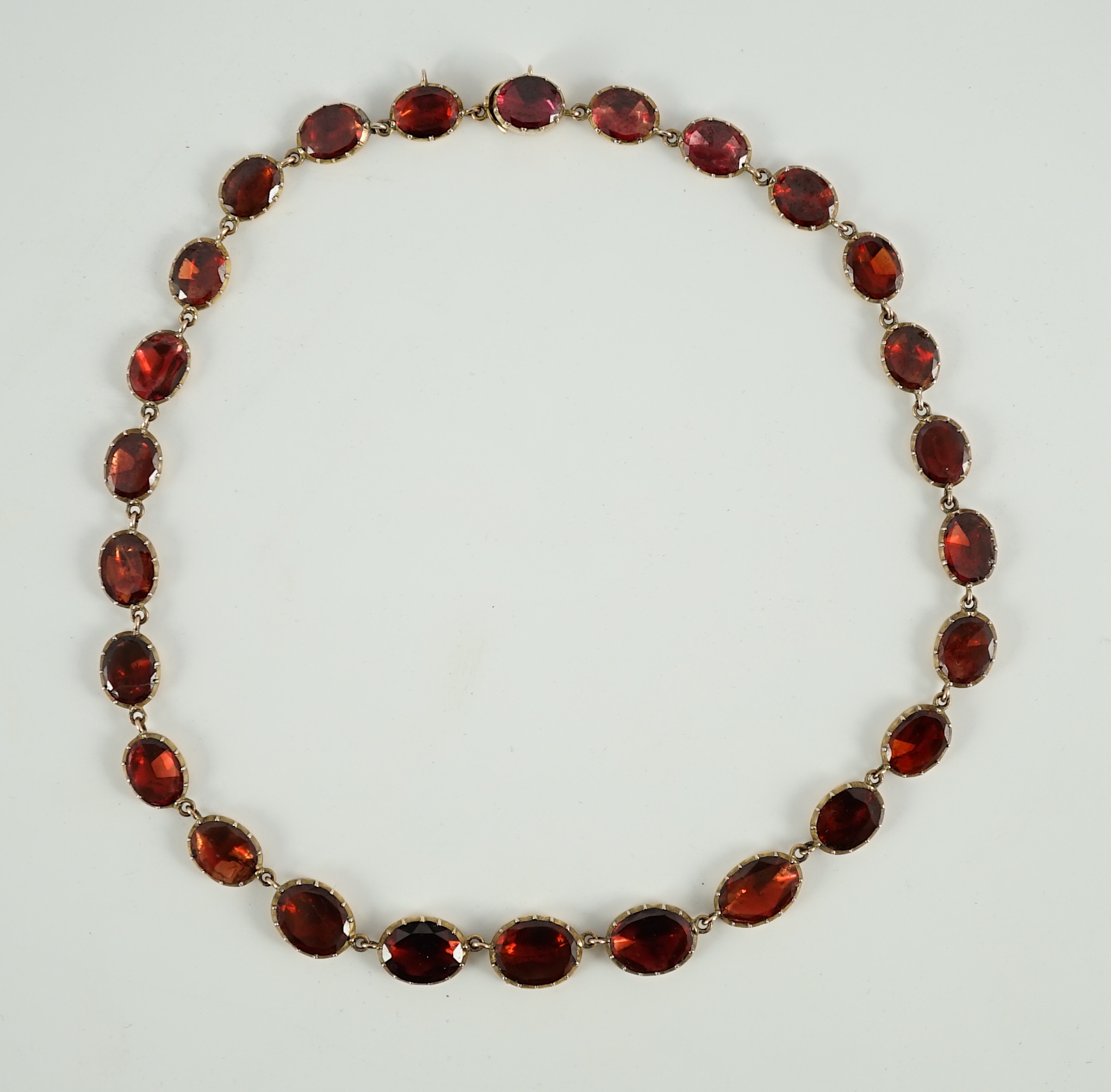 An early 19th century gold mounted graduated foil backed oval cut garnet set choker necklace